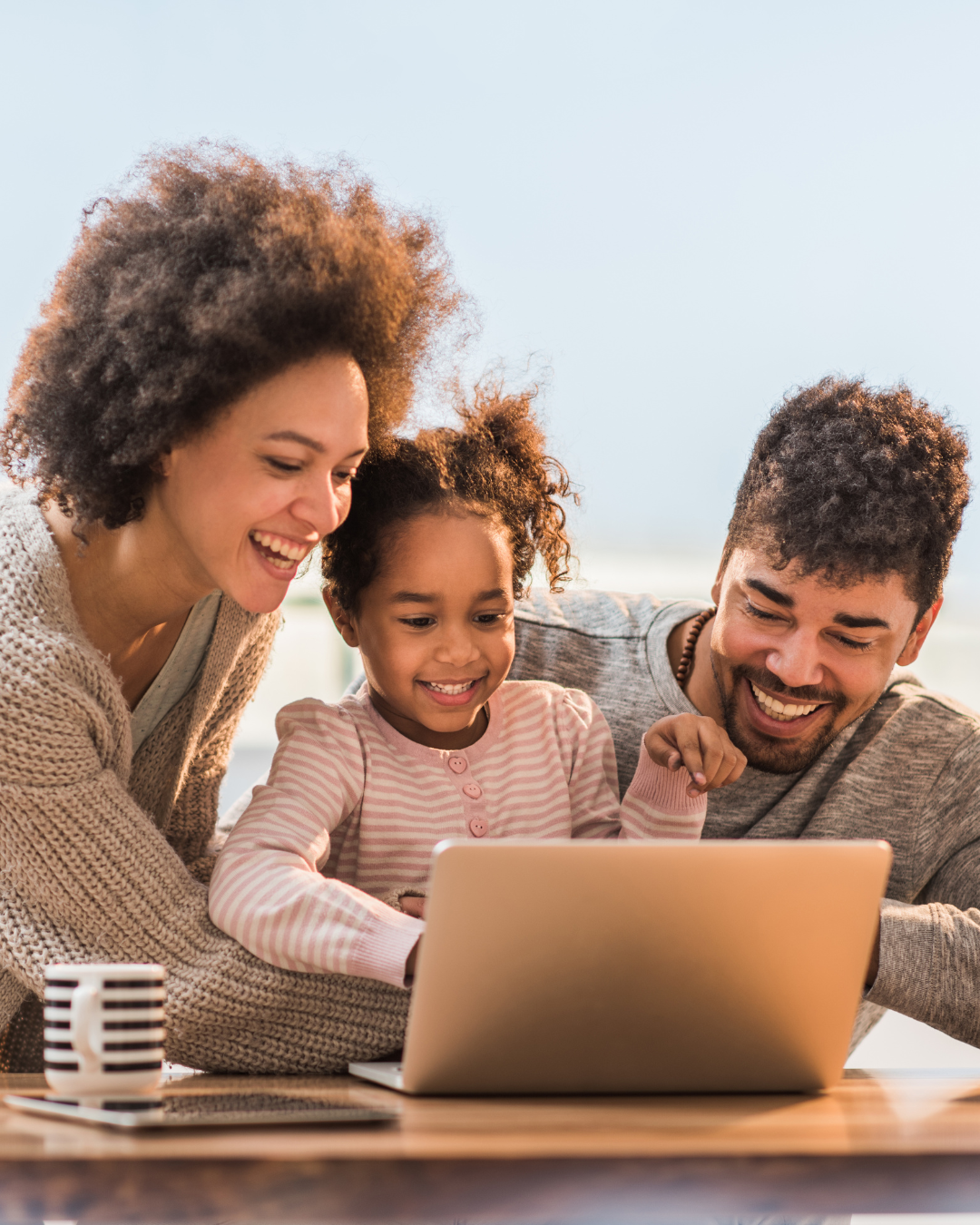 Family gathered around laptop supporting child in online learning at home, representing family engagement at Falcon View Online Minnesota.