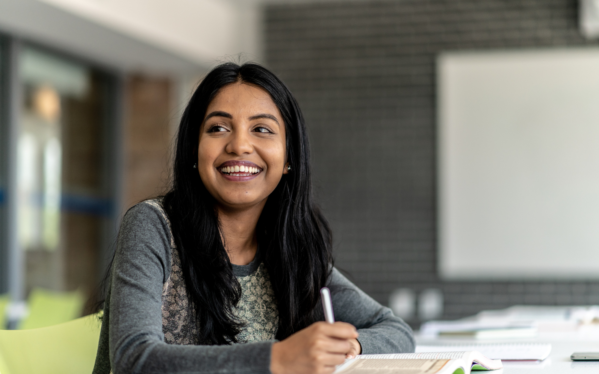 High school student smiling while studying and writing in a notebook at Falcon View Online, a tuition-free Minnesota online public school.