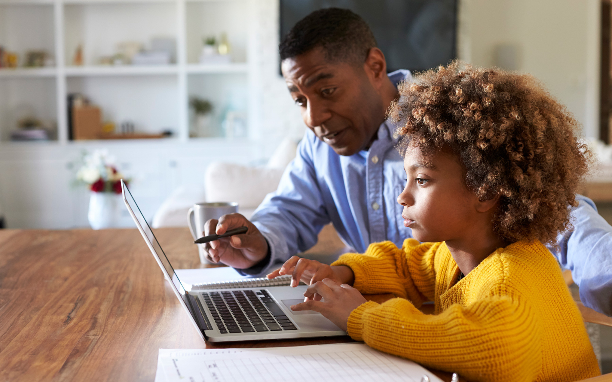 Minnesota parent helping child enroll in tuition-free K-12 online school at Falcon View Online while reviewing information on a laptop.