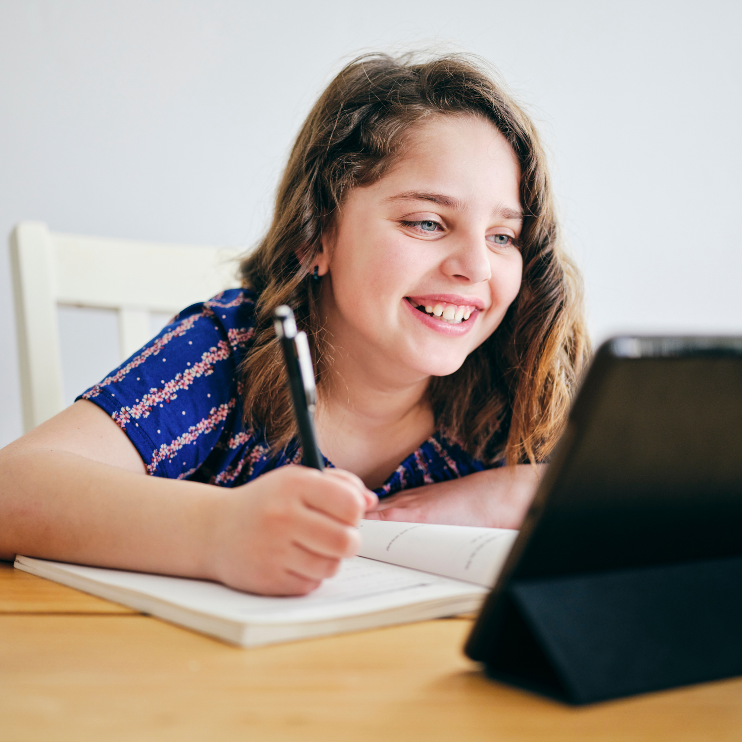 Minnesota middle school student participating in an online class from home while writing in a notebook, representing tuition-free K-12 online learning at Falcon View Online