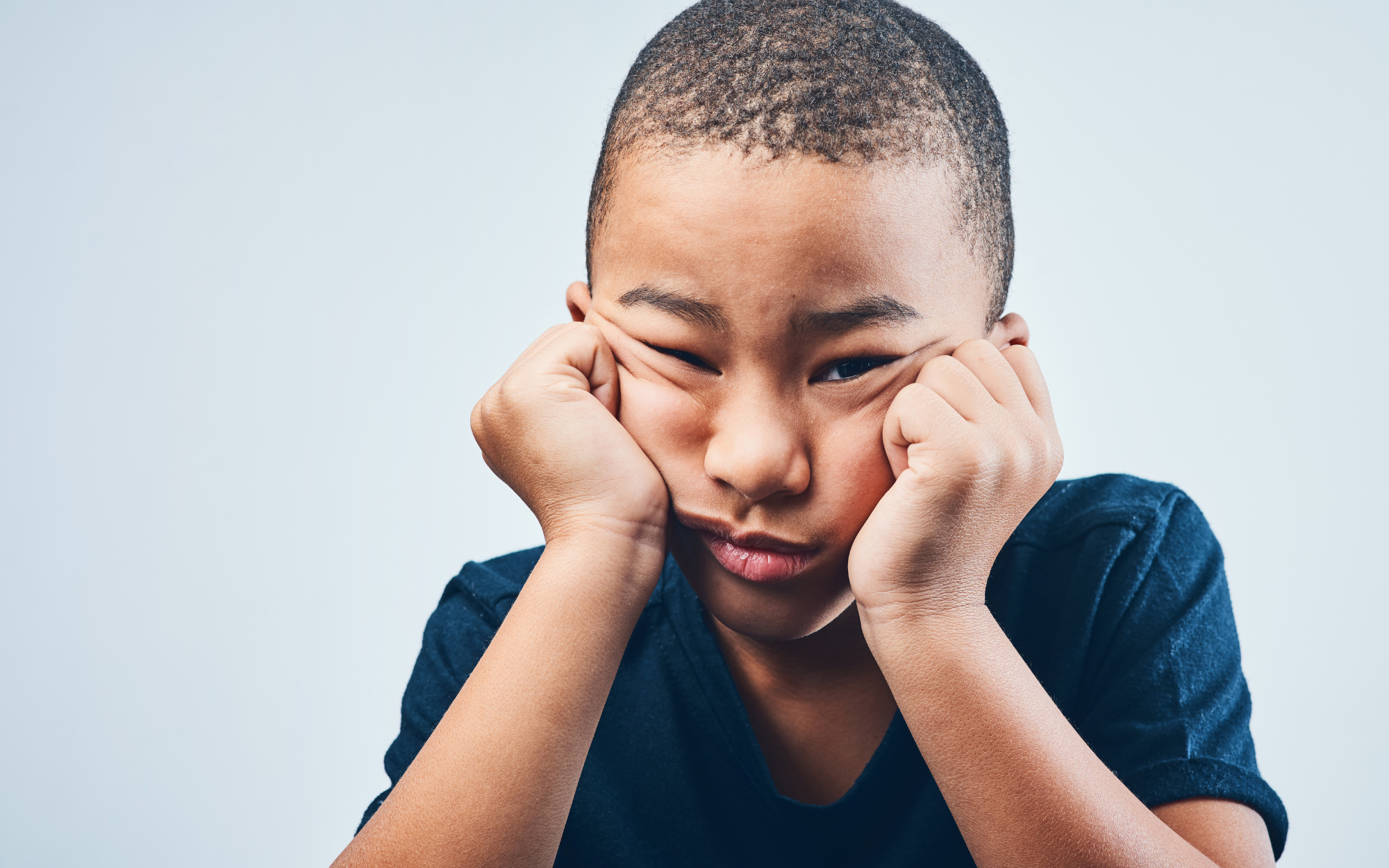 Frustrated student resting his face in his hands while struggling with motivation and school engagement, representing challenges often mistaken for laziness.<br />
