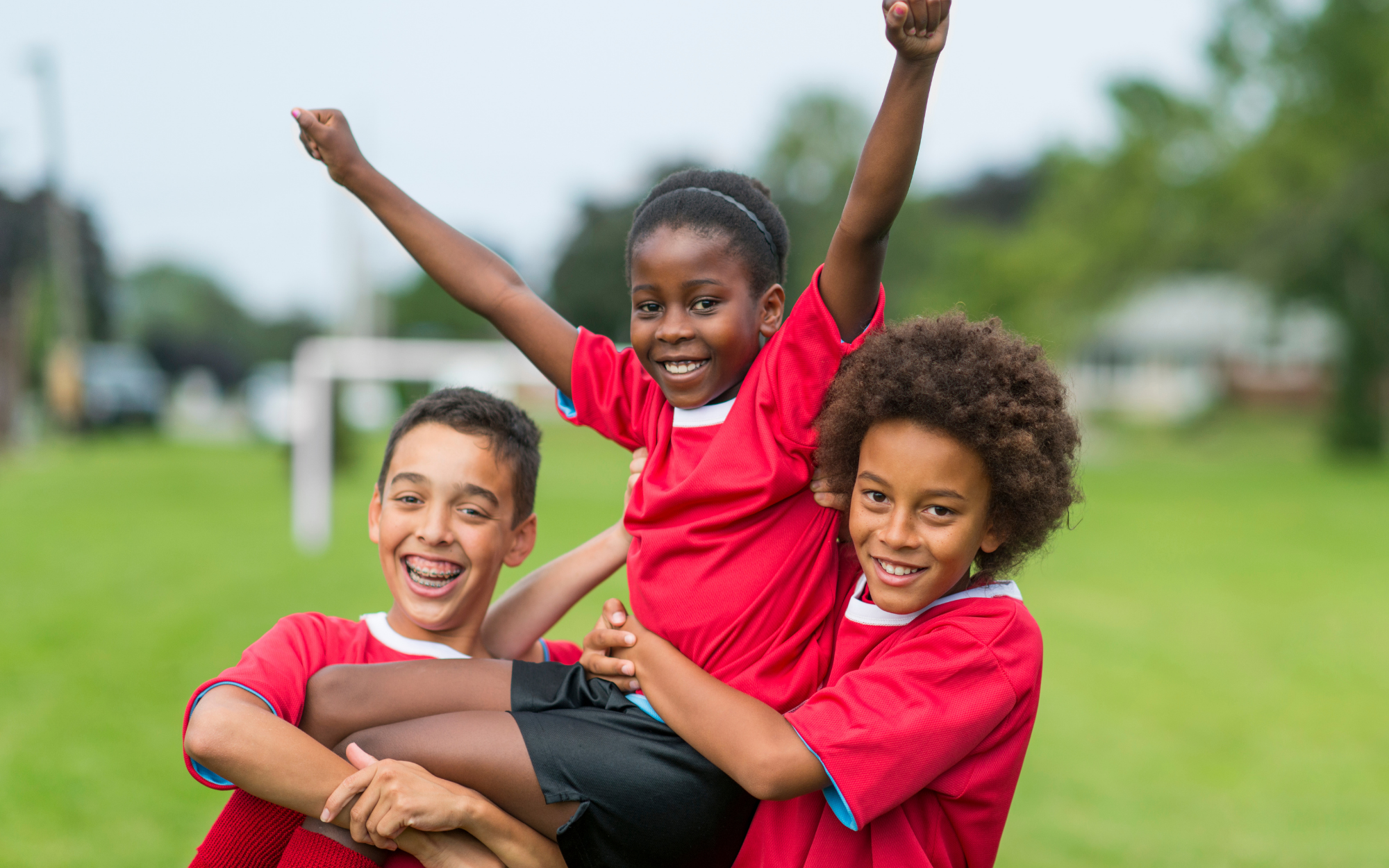 Children celebrating together on a sports field, representing extracurricular activities and social opportunities for online school students in Minnesota.