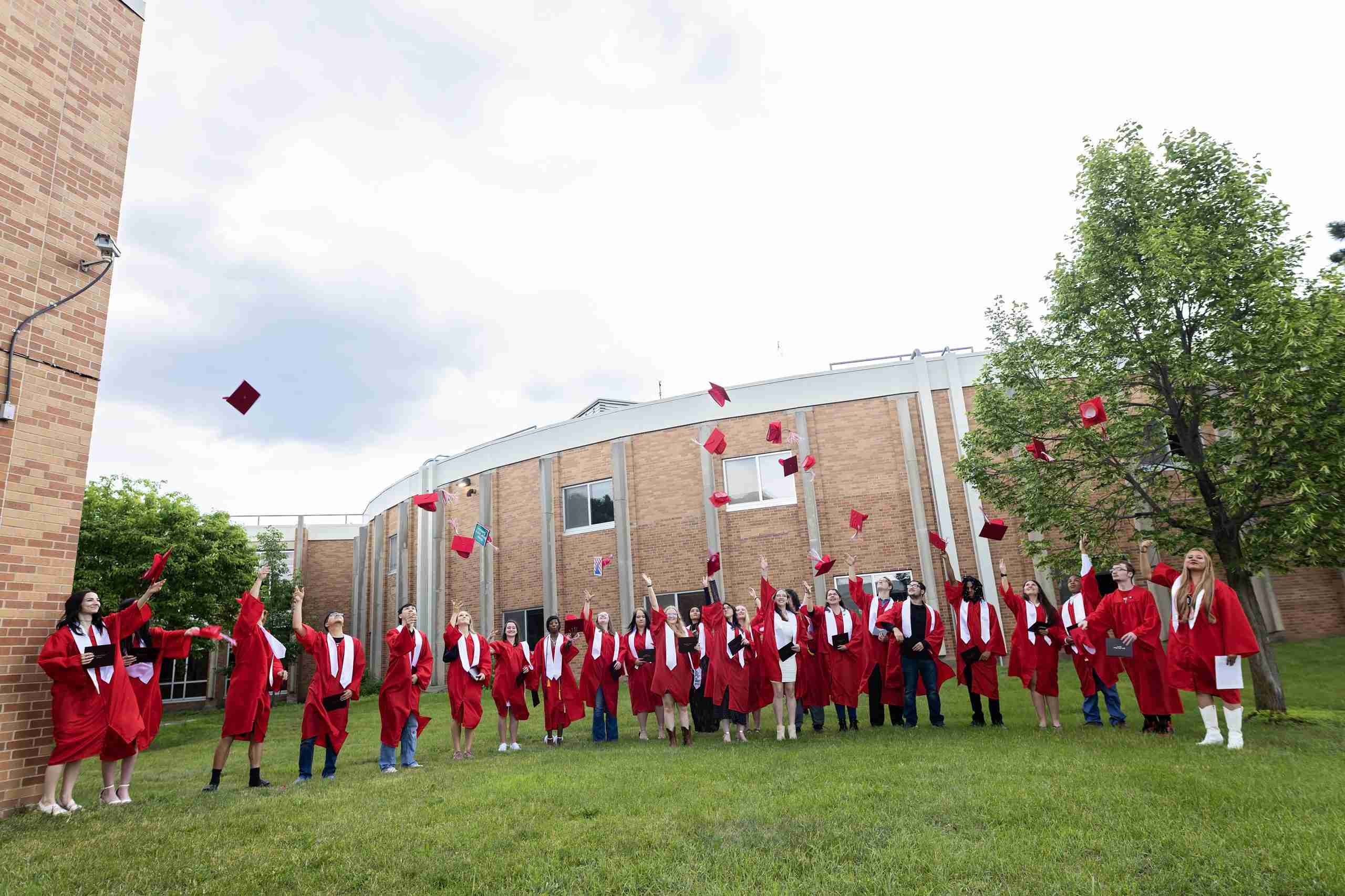 Falcon View Online Class of 2026 graduates celebrating graduation by tossing caps in the air at Wabasha-Kellogg Schools in Minnesota.