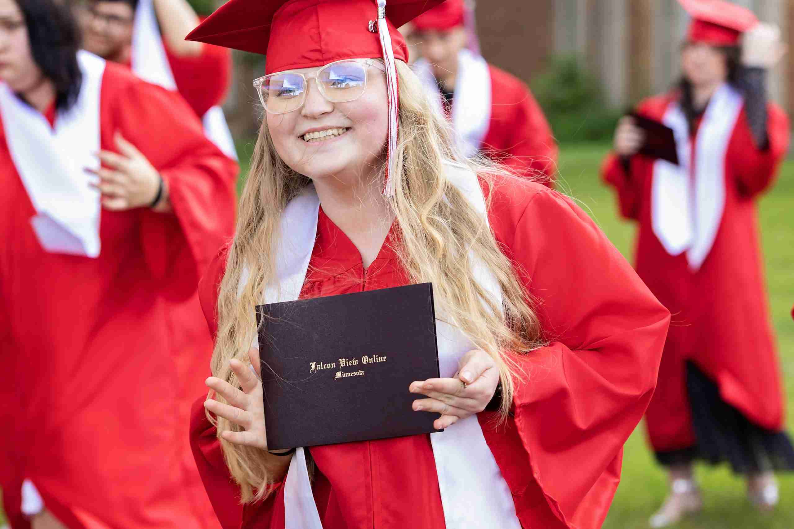 Falcon View Online School 2025 graduates celebrate by throwing their red caps into the air.