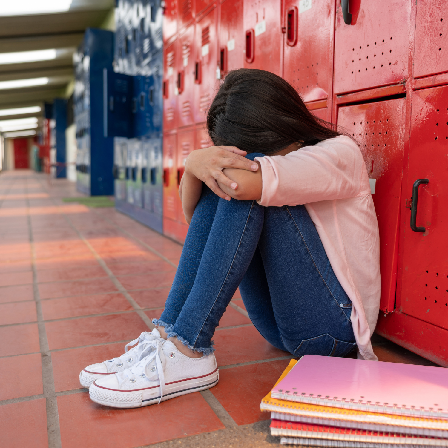Minnesota student sitting alone in a school hallway feeling overwhelmed and disconnected in a traditional school environment while exploring alternative education options.